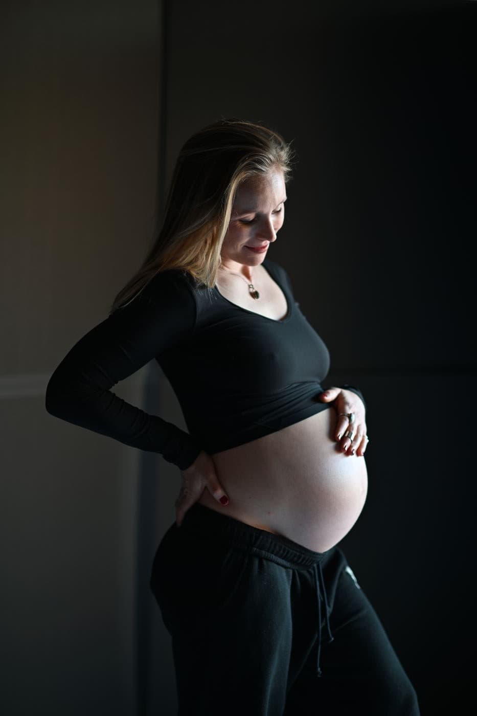 Madeleine pregnant, hands resting on her belly