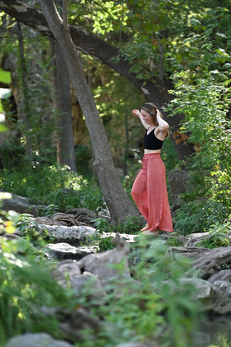 Madeleine Gray, founder of Wild Roots, standing barefoot in the woods